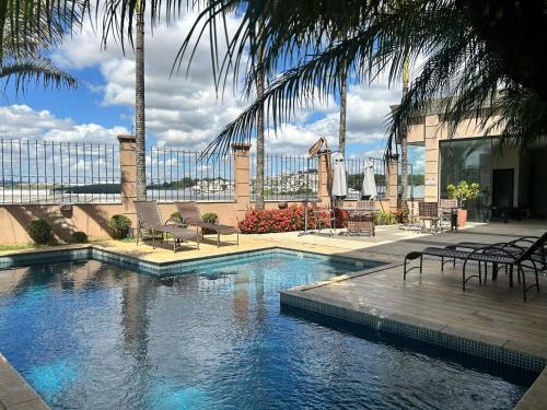una piscina con sedie e palme in un edificio di Class Hotel Varginha a Varginha