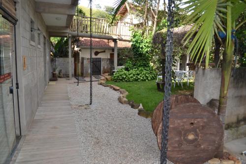 a porch with a swing and a garden at Pousada Rota dos Pássaros in São Bento do Sapucaí