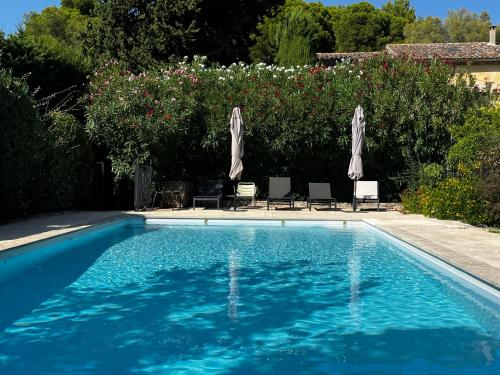 - une piscine avec deux parasols dans une cour dans l'établissement MAISON À MAUSSANE-les-ALPILLES, à Maussane-les-Alpilles