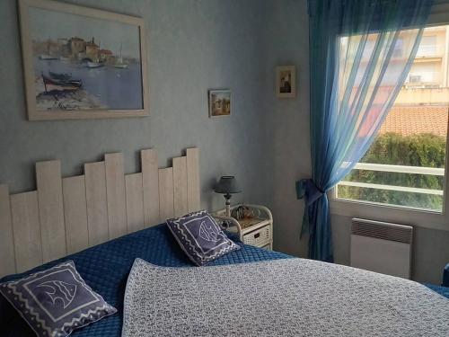 une chambre avec un lit avec des draps bleus et une fenêtre dans l'établissement Appartement T2 à Arcachon à 400m de la plage avec balcon et parking privé - FR-1-433-48, à Arcachon
