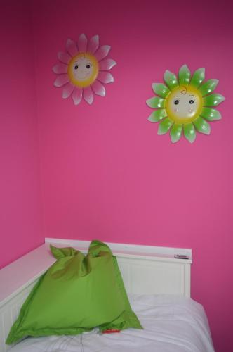 two flowers on a pink wall above a bed at Echappée Belle in Jalhay