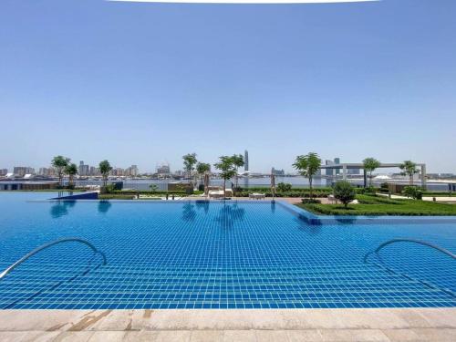 a large swimming pool with blue water at SettlerHomes - Chic Creek Edge 1BR With Harbour View in Dubai