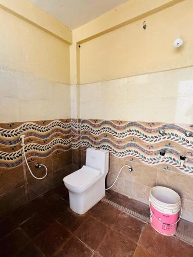 a bathroom with a toilet and a trash can at Sampigeheritage resot in Koppal