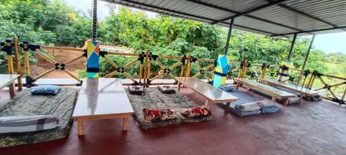 a pavilion with benches and tables on a deck at Sampigeheritage resot in Koppal