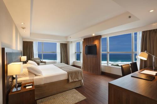 a large hotel room with a bed and a desk at Windsor Oceanico Hotel in Rio de Janeiro