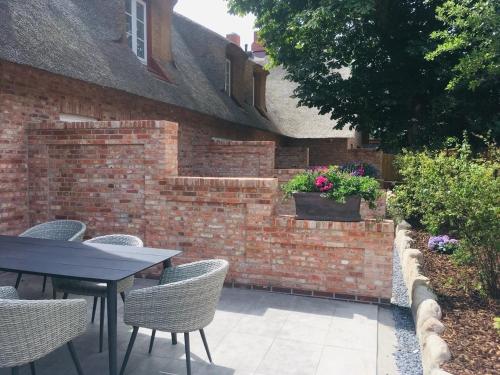 eine Terrasse mit Tisch und Stühlen und einer Backsteinmauer in der Unterkunft Haus Boldix Whg 5 Martinique in Boldixum