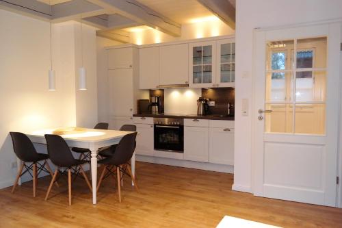 eine Küche mit weißen Schränken und einem Tisch und Stühlen in der Unterkunft Haus Boldix Whg 5 Martinique in Boldixum