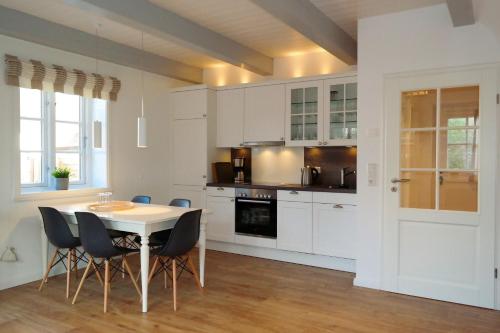 eine Küche mit weißen Schränken und einem Tisch und Stühlen in der Unterkunft Haus Boldix Whg 6 St Barth in Boldixum