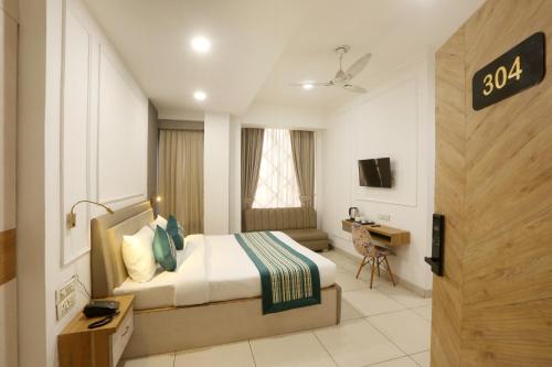 a hotel room with a bed and a desk at Hotel Emerald Suites & Banquet By Aura in Noida