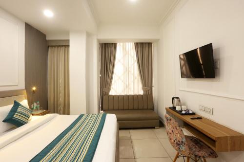 a hotel room with a bed and a desk and a television at Hotel Emerald Suites & Banquet By Aura in Noida