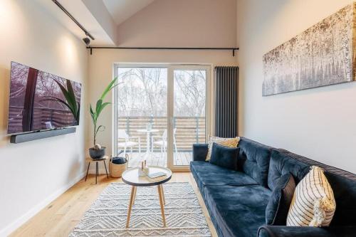 a living room with a blue couch and a table at Apartament BLACK PEARL Baltic Concept Dźwirzyno in Dźwirzyno
