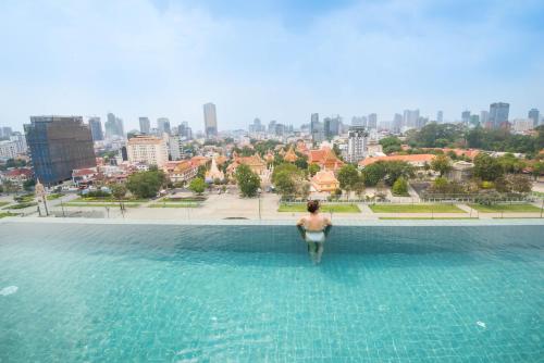 a woman in a swimming pool with a city in the background at GLOW PARK HOTEL Grand Royal Palace in Phnom Penh