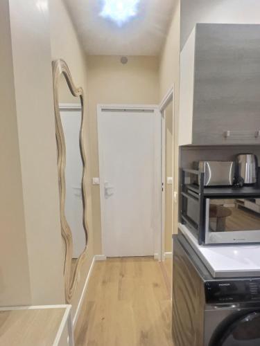 a kitchen with a white door and a microwave at Le Nid de Clichy in Clichy