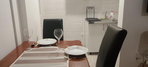 a dining room table with two plates and wine glasses at Apartman Danica Bijeljina in Bijeljina