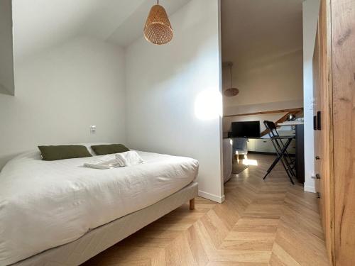 une chambre blanche avec un lit et un bureau dans l'établissement Studio Maya, à Donville-les-Bains