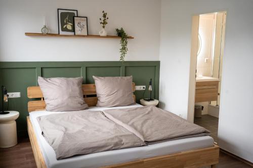 a bed with a green headboard in a bedroom at TRIMOSA - Apartments & Homes in Bitburg
