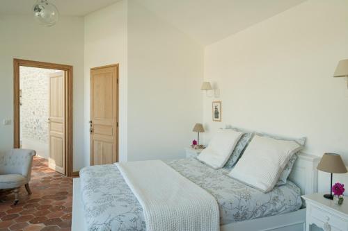 a white bedroom with a bed and a chair at Depuis la verrière in Bleury