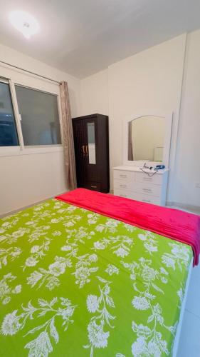 a bedroom with a bed with a green and white bedspread at Furnished room available for rent in new shahama for short stay in Abu Dhabi