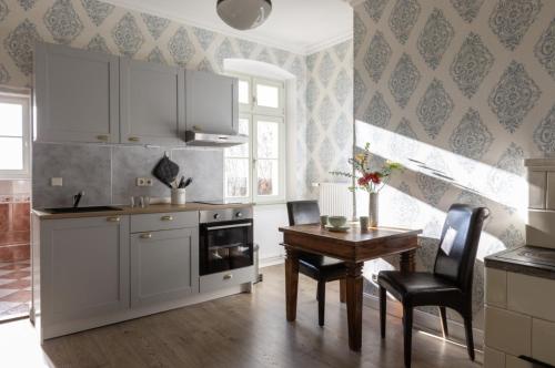 a kitchen with white cabinets and a table with chairs at THE GATE GARDEN Hotel in Berlin