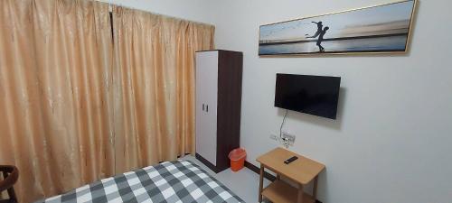 a room with a bed and a television and a table at 大衛城民宿 in Shan-ch'ien