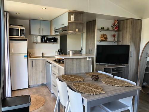 une cuisine avec une table et des chaises ainsi qu'une télévision dans l'établissement L' Escapade, au Muy