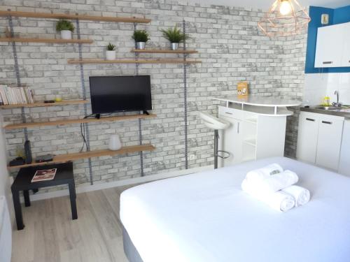 Cette chambre comprend un lit blanc et une télévision. dans l'établissement 3 Rois - Joli studio 2 pers, place de parking, à Nantes