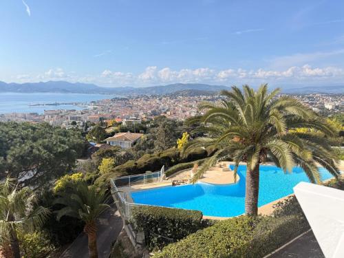 une piscine avec un palmier et une ville dans l'établissement Panoramic Sea View Cannes renovated 3 bedrooms - Swimming Pool, à Cannes