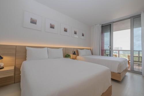 ハランデール・ビーチにあるLuxury Miami Apartment Beach and Poolside drinks 2308のベッドが2つと大きな窓があるホテルの部屋