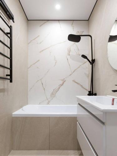 La salle de bains est pourvue d'une baignoire blanche et d'une lampe noire. dans l'établissement Grande maison avec meubles 12, à Les Allues