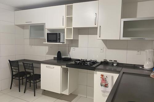 eine Küche mit weißen Schränken und einer schwarzen Arbeitsplatte in der Unterkunft Próx a orla, 14 pessoas, ar condicionado e garagem in Petrolina