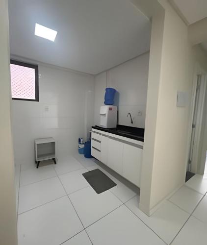 a white kitchen with a sink and a microwave at Na Orla de Petrolina, ar condicionado e elevador in Petrolina
