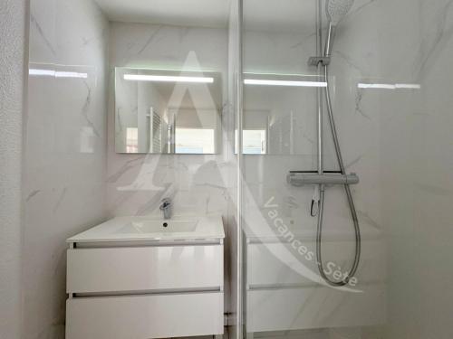 une salle de bain blanche avec une douche et un lavabo dans l'établissement T2 COIN CHAMBRE, TERRASSE 1ERE LIGNE MER, PISCINE, à Sète