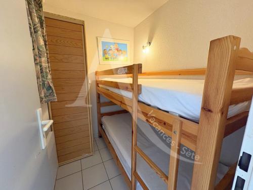 - 2 lits superposés dans une petite chambre avec une porte dans l'établissement T2 COIN CHAMBRE, TERRASSE 1ERE LIGNE MER, PISCINE, à Sète