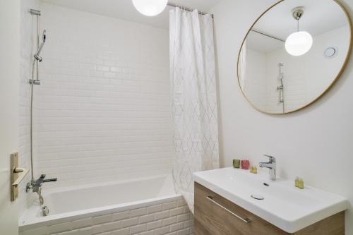 une salle de bain avec une baignoire, un lavabo et un miroir dans l'établissement New & Cozy T2 with Balcony - Paris 18 Montmartre, à Paris