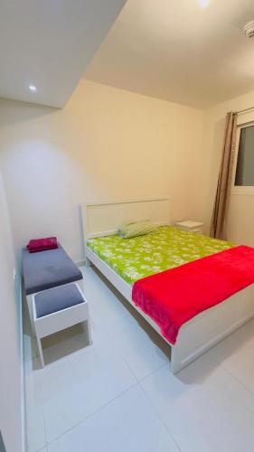 a bedroom with a bed with a red and green blanket at Furnished room available for rent in new shahama for short stay in Abu Dhabi