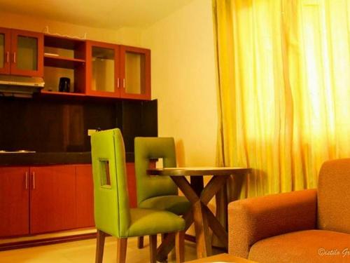 a living room with a green chair and a table at Hidden Pearl Hotel (Janus Luxury Suites) in Angeles