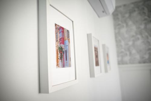 a row of framed pictures on a wall in a room at Cliff Edge Apartment in Xaghra in Taʼ Bullara