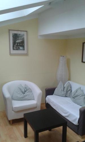 a living room with two white chairs and a table at Binderhof in Sankt Johann in Tirol