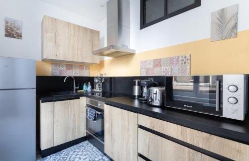 a kitchen with a black counter top and a microwave at Les Aiguilles Dorées #Hypercentre#Comfort in Clermont-Ferrand