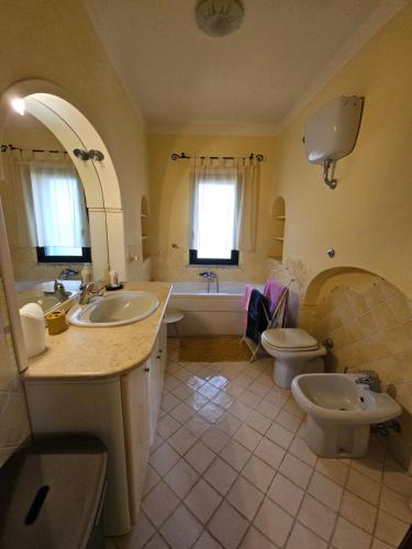 ein Badezimmer mit zwei Waschbecken und einer Badewanne und einer Toilette in der Unterkunft Prestigiosa villa La Cinta in San Teodoro