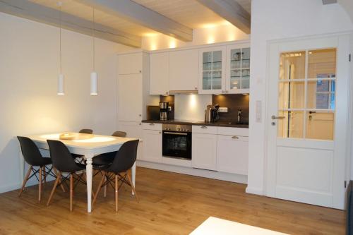 eine Küche mit weißen Schränken und einem Tisch und Stühlen in der Unterkunft Haus Boldix Whg 4 Cayman in Boldixum