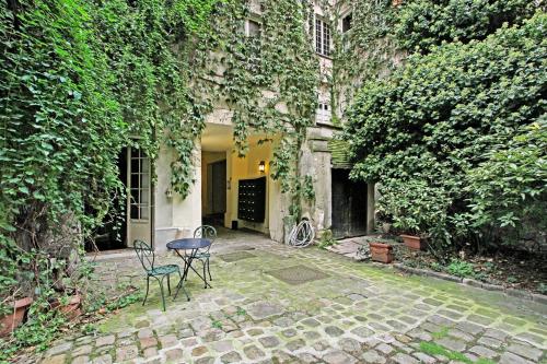- une terrasse avec 2 chaises et une table en face d'un bâtiment dans l'établissement Loft avec terrasse au coeur du Marais, à Paris