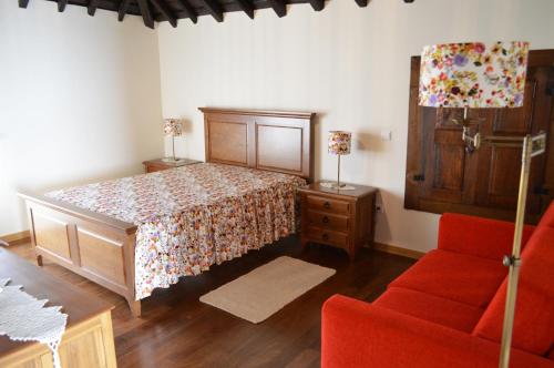 1 dormitorio con 1 cama y 1 sofá rojo en Casa de Campo das Sécias en Vilas Boas