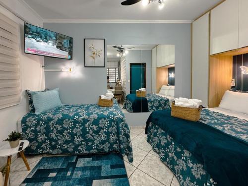 a hotel room with two beds and a television at Apartamento Conforto e Prático in Maringá