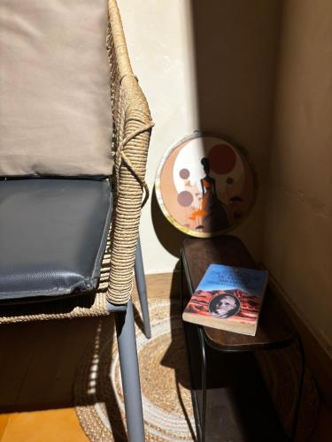 a chair next to a table with a book on it at 1111 Villa - The Human Happiness project - MUKTESHWAR - ------------- ---------------- --------------------- ------------------------------ --------------------------------------------- ------------Jacuzzi - Private Property with Garden and Orchard in Mukteswar