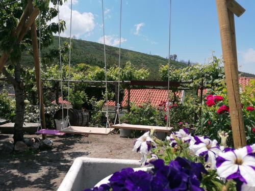 a garden with purple and white flowers and a table at Casinha Pôr do Sol in Aldeia das Dez