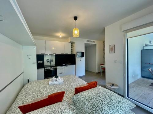 een kamer met een bed met rode kussens en een keuken bij Charming Studio with Parking near Monaco in Beausoleil