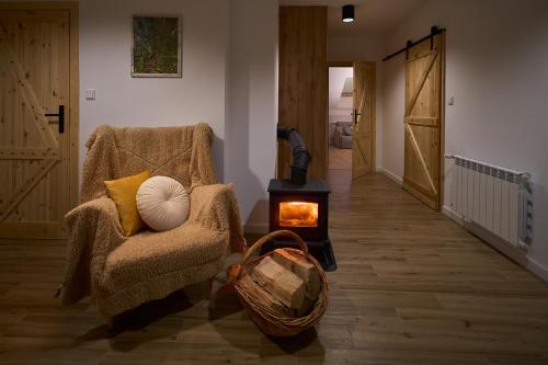 a living room with a chair and a wood stove at Brzozowy Zakątek in Posada Górna
