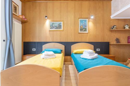 two beds in a room with wooden walls and wooden floors at All'Uno, Taio Ospitar in Taio