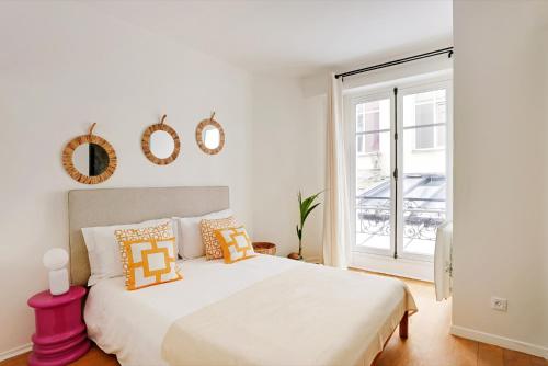 une chambre blanche avec un grand lit et une fenêtre dans l'établissement 2 pièces au coeur de Montmartre - proche Sacré Coeur, à Paris